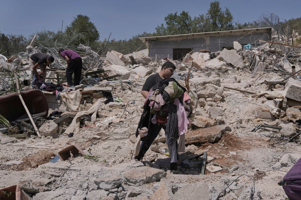 A Palestinian youth carries clothes as he walks over the rubble of a house demolished by the Israeli army in the West Bank village of Beit Sira. Photo: AP